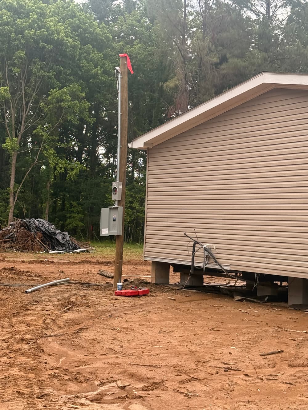 Exterior electrical service equipment mounted on a pole beside a home